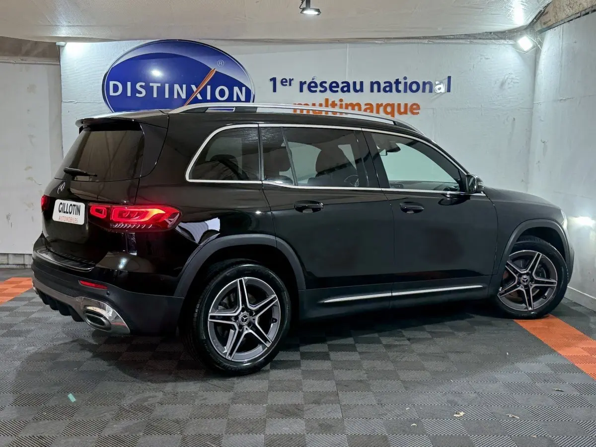 Mercedes GLB 200 d AMG Line noir vue de profil côté droit, avec jantes alliage et feux arrière allumés dans un showroom.