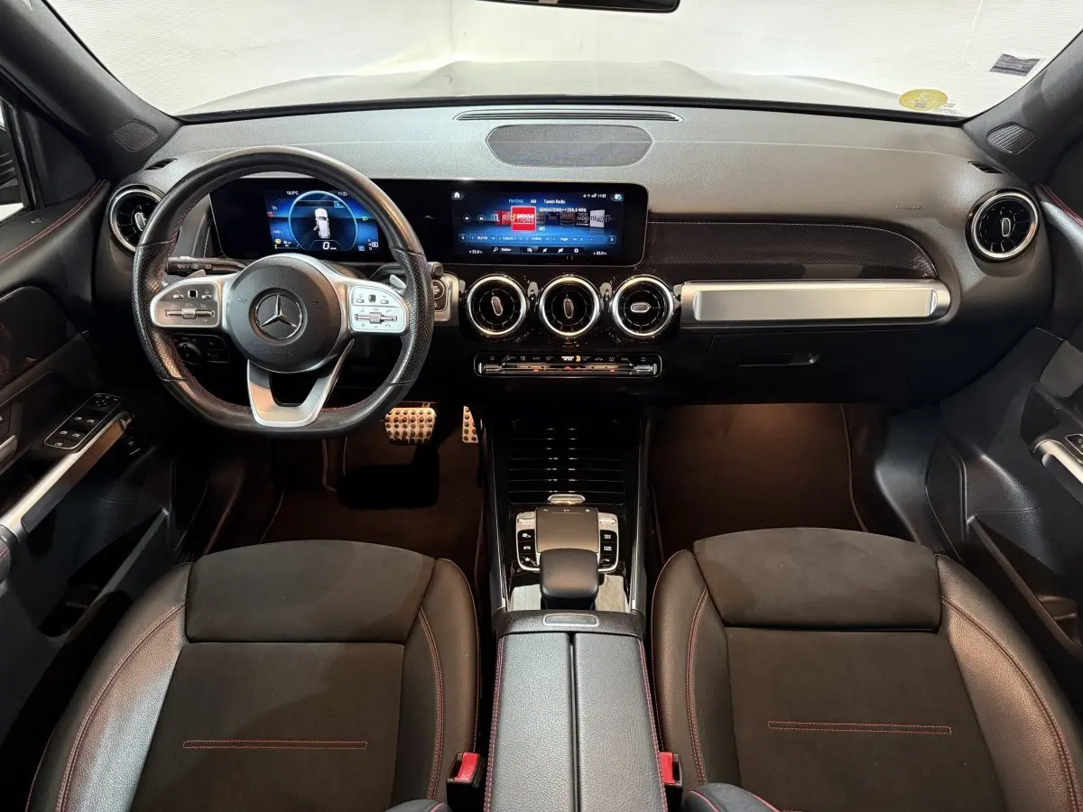 Vue intérieure frontale du tableau de bord et volant cuir noir du Mercedes GLB 200 d AMG Line avec écrans digitaux.