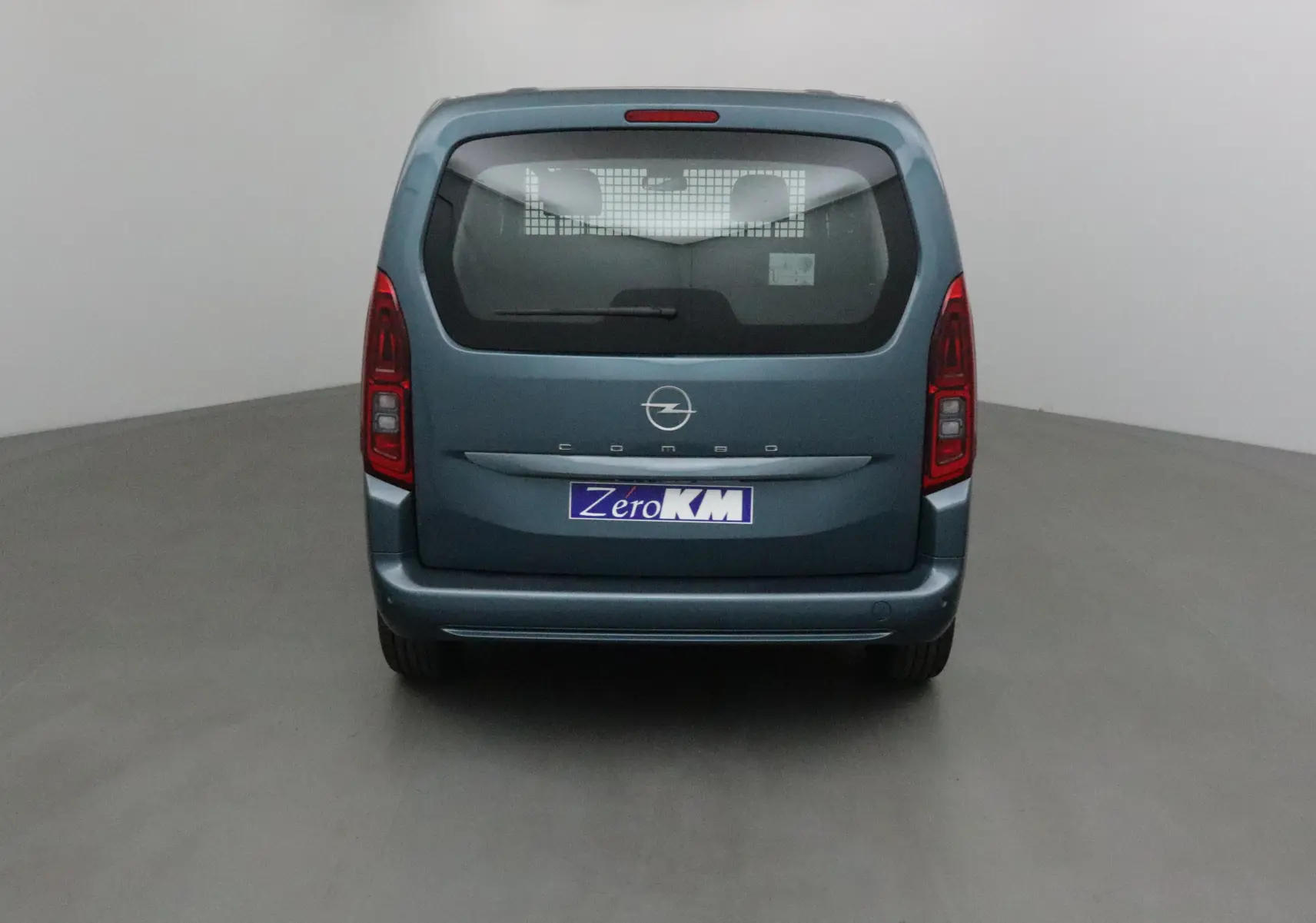 Vue arrière d'un Opel Combo Life bleu Kiama avec vitre arrière et grille de séparation visible.