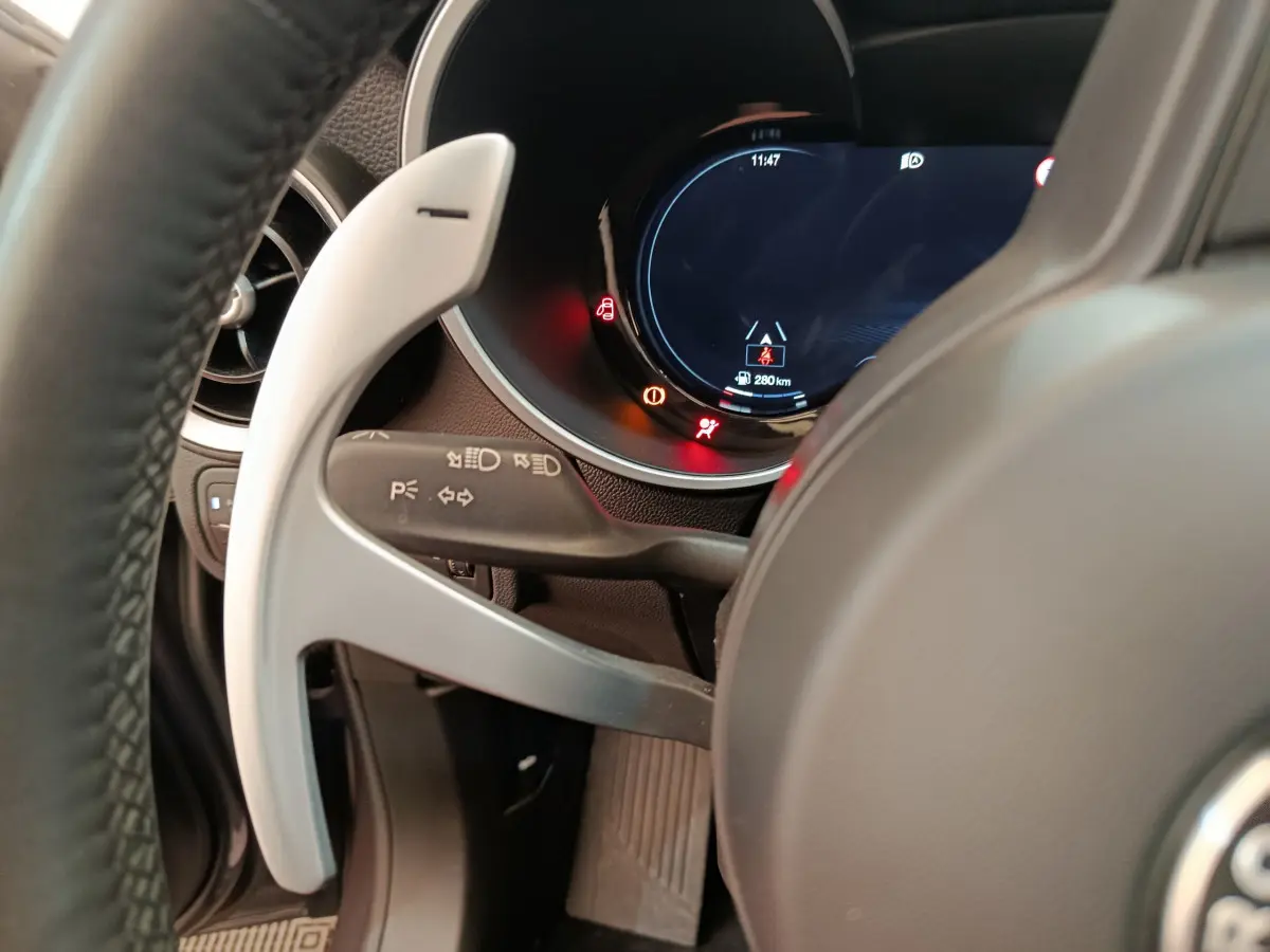 Gros plan sur le volant et le combiné d'instruments digital de l'Alfa Romeo Stelvio gris foncé, côté conducteur.