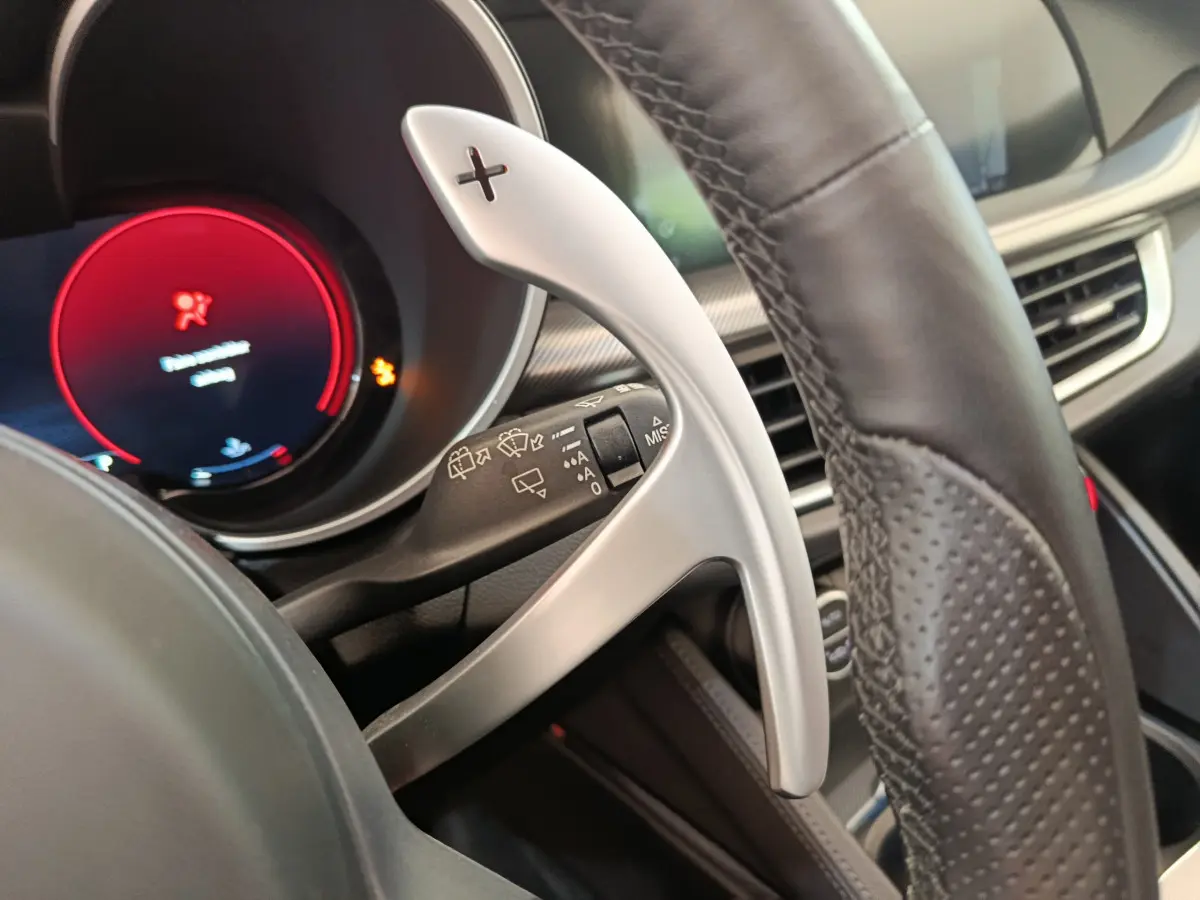 Gros plan sur la palette de changement de vitesse droite en aluminium et cuir du tableau de bord de l'Alfa Romeo Stelvio gris foncé.