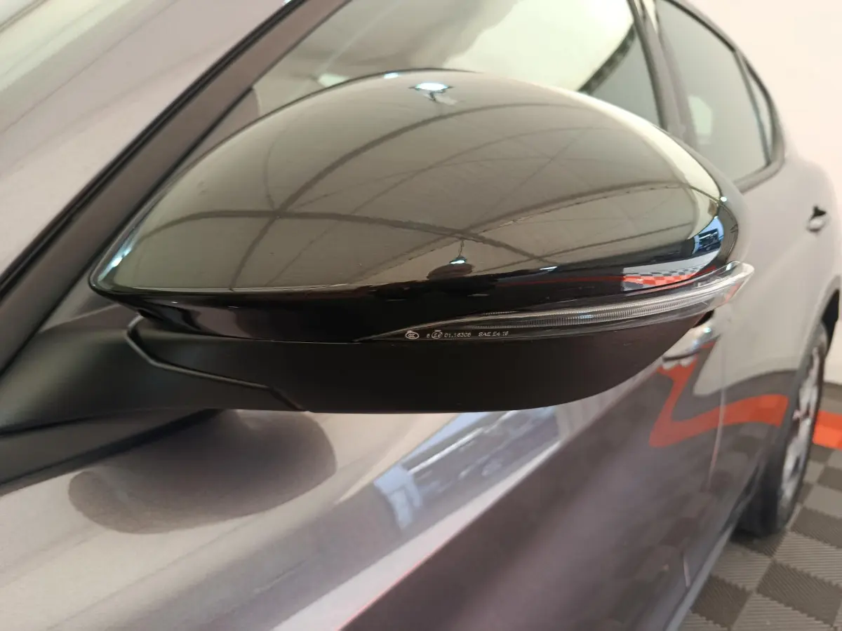 Rétroviseur droit noir brillant avec clignotant intégré sur Alfa Romeo Stelvio gris foncé vue rapprochée côté droit.