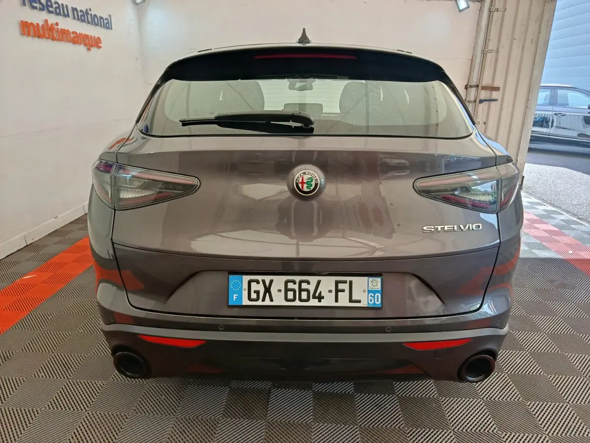 Vue arrière d'un Alfa Romeo Stelvio gris foncé avec feux LED et double sortie d'échappement intégrée.