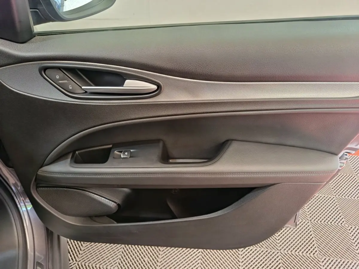Gros plan sur la porte côté gauche gris foncé de l'Alfa Romeo Stelvio avec poignée argentée et commandes verrouillage.
