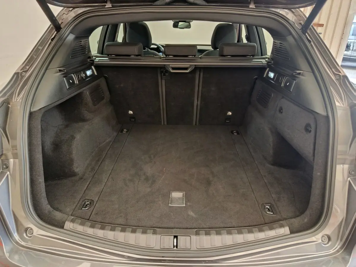 Coffre ouvert vu de l'arrière d'un Alfa Romeo Stelvio gris foncé, intérieur spacieux et tapis noir.
