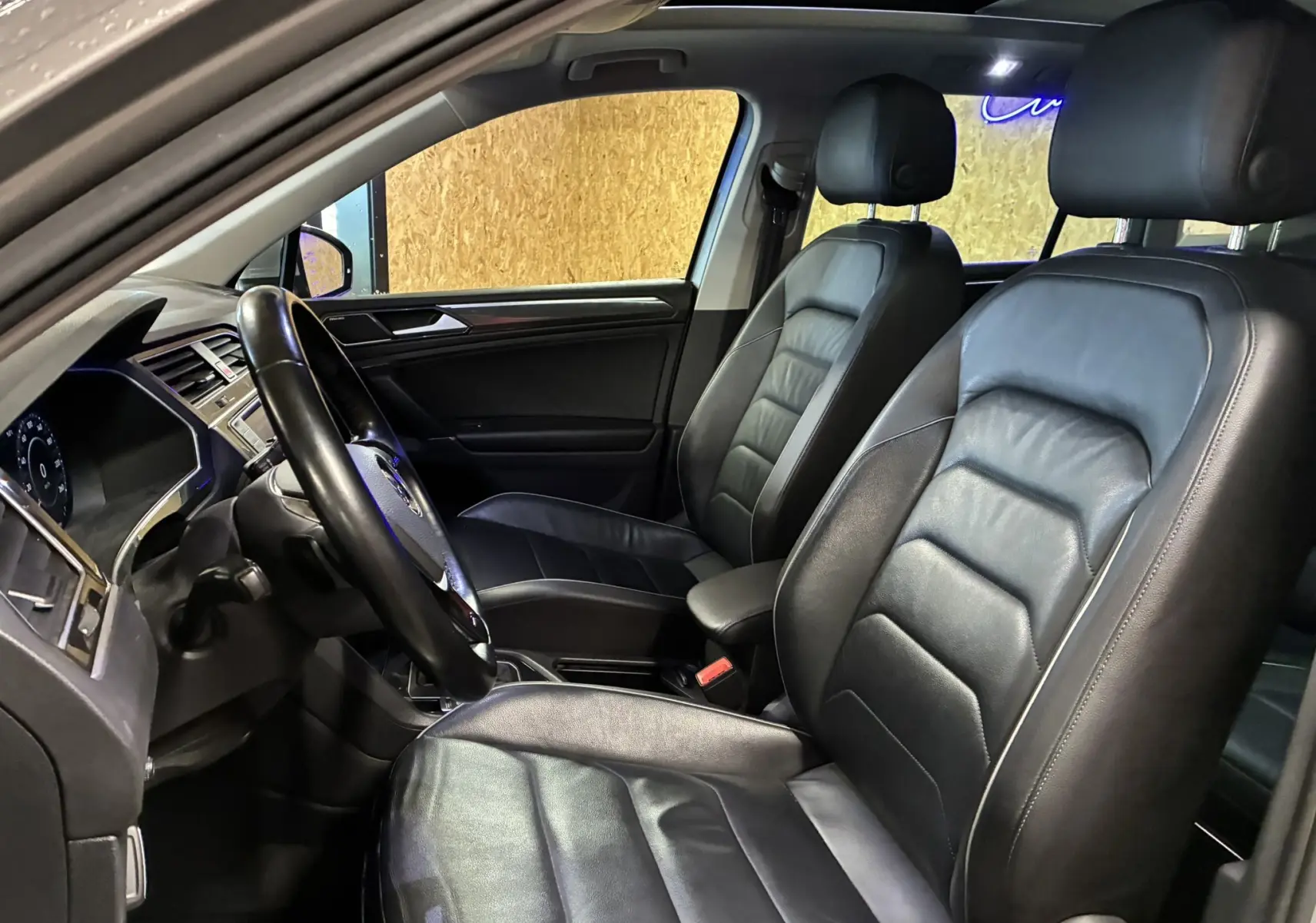 Vue intérieure côté conducteur du Volkswagen Tiguan 2.0 TDI 150 Carat 2017 avec sièges cuir noir et tableau de bord moderne.