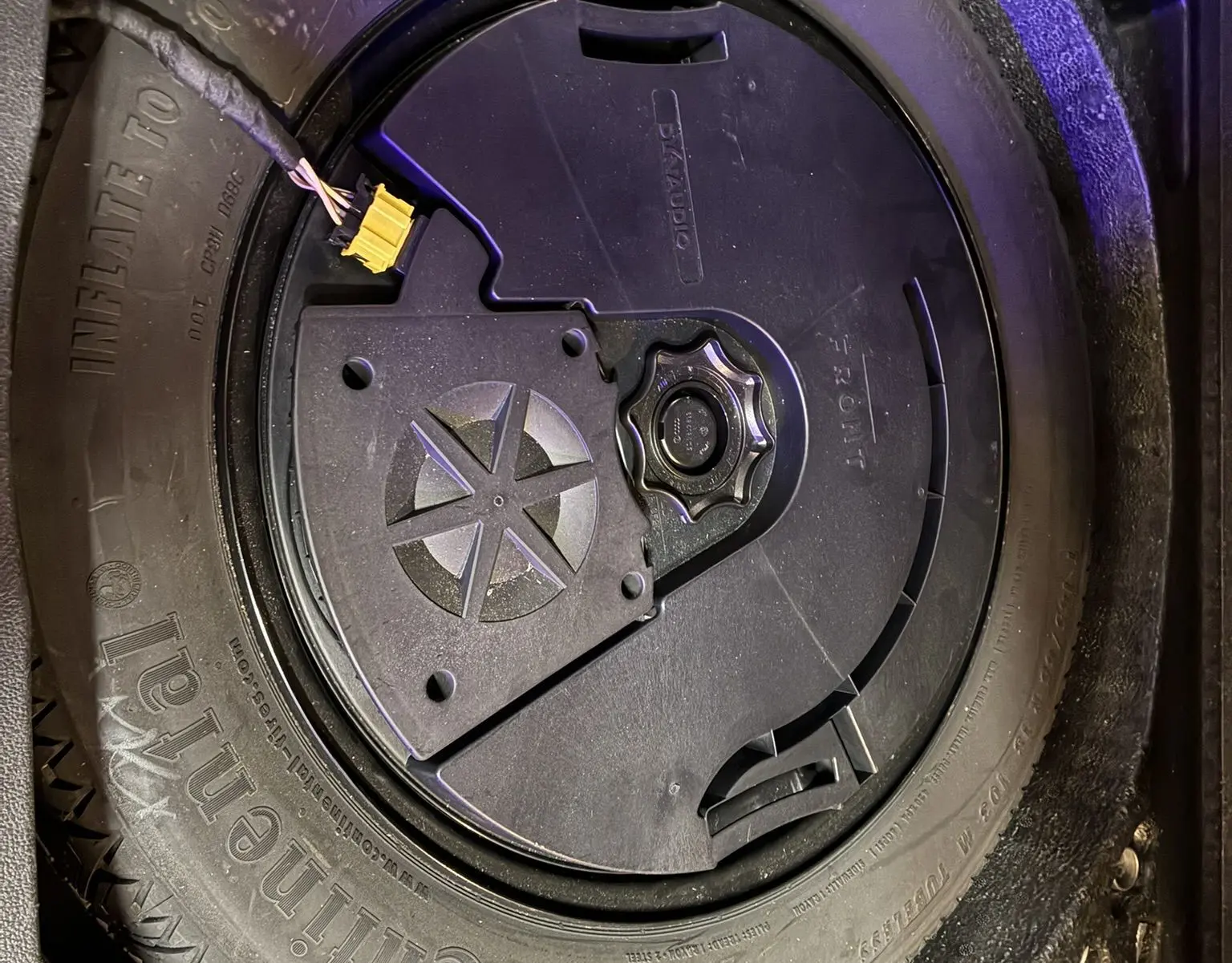 Gros plan sur la roue de secours noire dans le coffre d’un Volkswagen Tiguan gris 2017, avec outil de fixation visible.