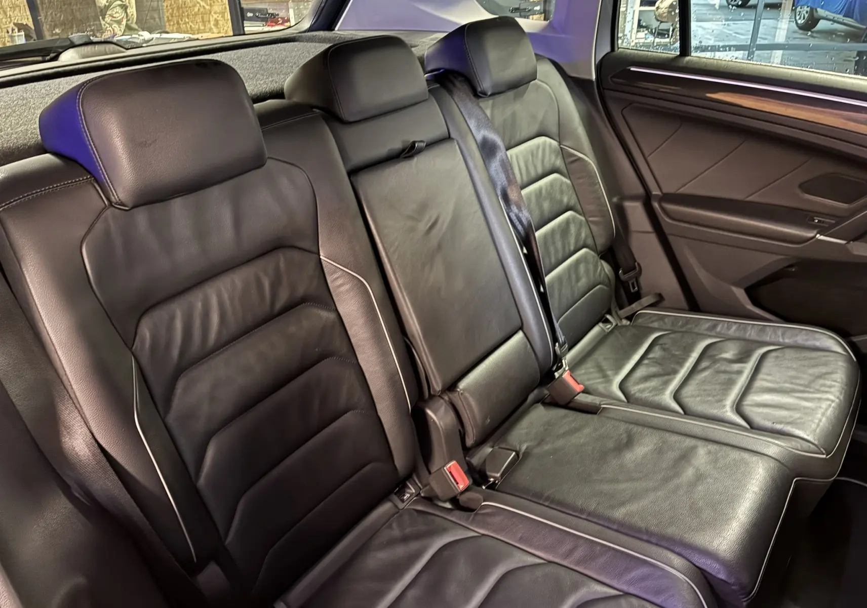 Vue intérieure des sièges arrière en cuir noir du Volkswagen Tiguan 2.0 TDI 150 Carat, avec accoudoir central relevé.