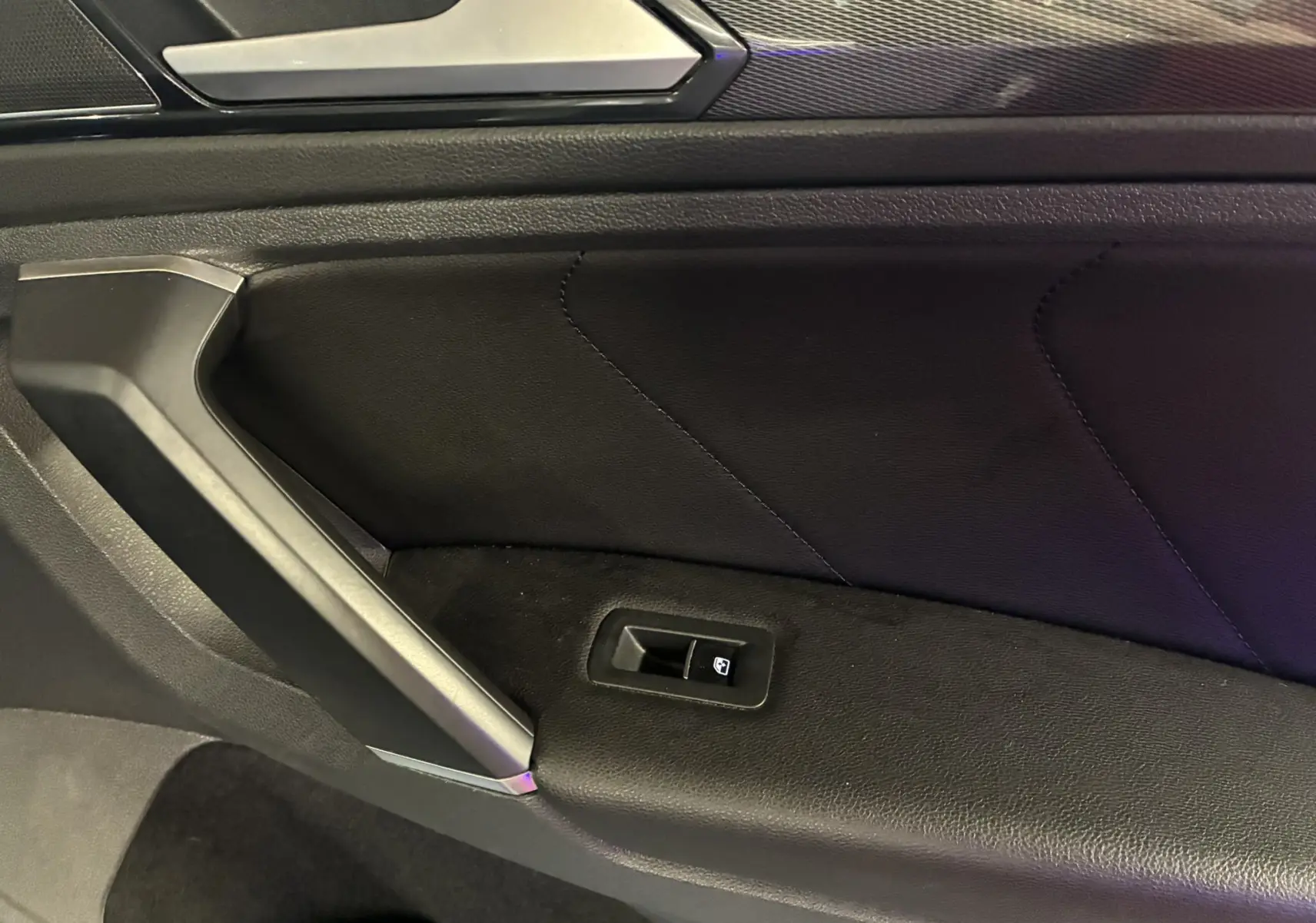 Détail de la porte intérieure côté gauche du Volkswagen Tiguan 2.0 TDI 150 Carat 2017 avec garniture cuir noir et commande de lève-vitre.