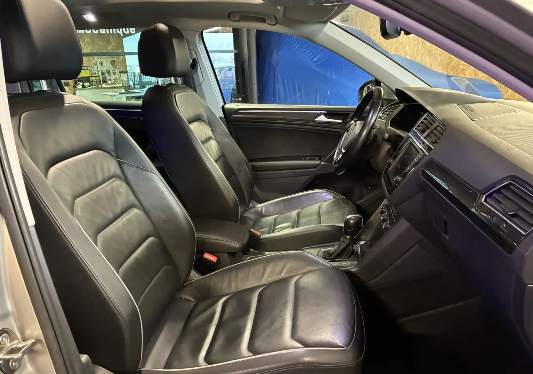 Vue intérieure côté conducteur du Volkswagen Tiguan gris 2017, avec sièges en cuir noir et tableau de bord moderne.