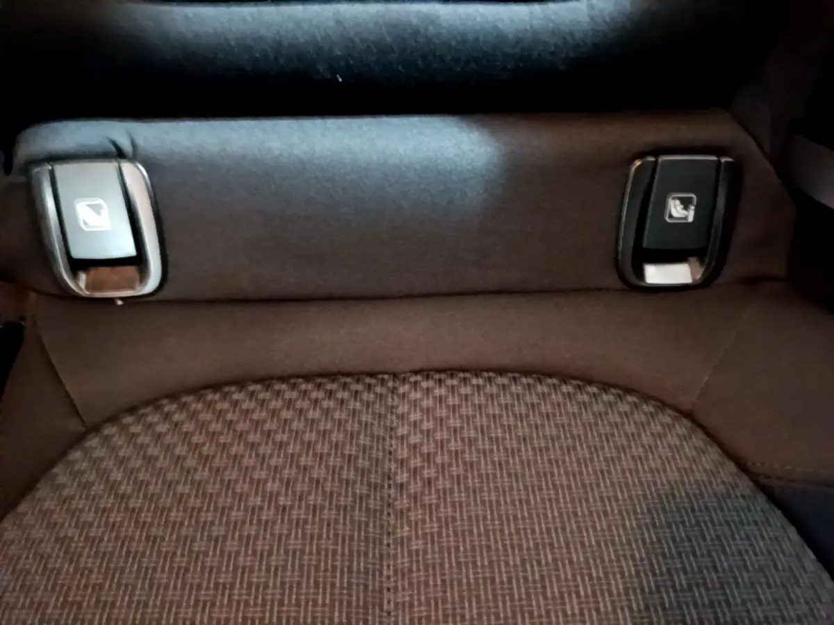 Détail des commandes de rabattement des sièges arrière sur banquette tissu gris foncé d'une BMW X2 sDrive18i Lounge.