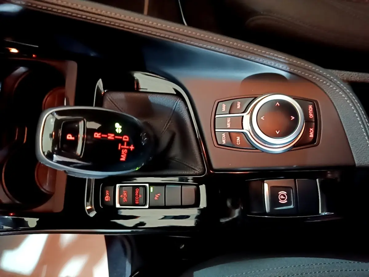 Vue rapprochée de la console centrale noire de la BMW X2 sDrive18i Lounge DKG7 avec levier de vitesse automatique et molette de commande.