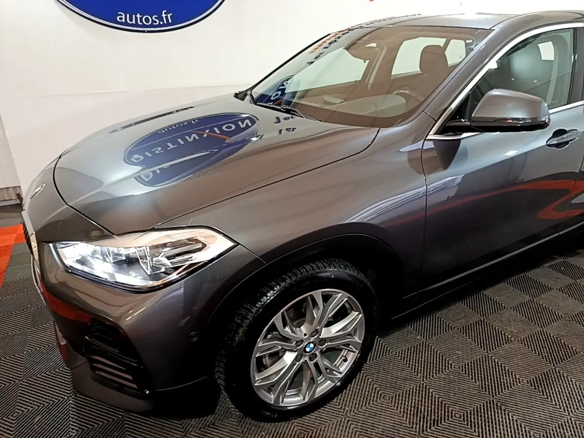 Vue 3/4 avant droit d’un BMW X2 sDrive18i Lounge gris foncé avec phares LED et jantes alliage visibles.