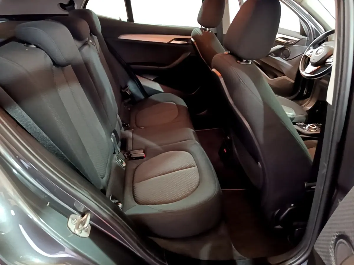 Vue intérieure côté gauche montrant les sièges arrière noirs et l'avant du BMW X2 sDrive18i Lounge DKG7 gris foncé.