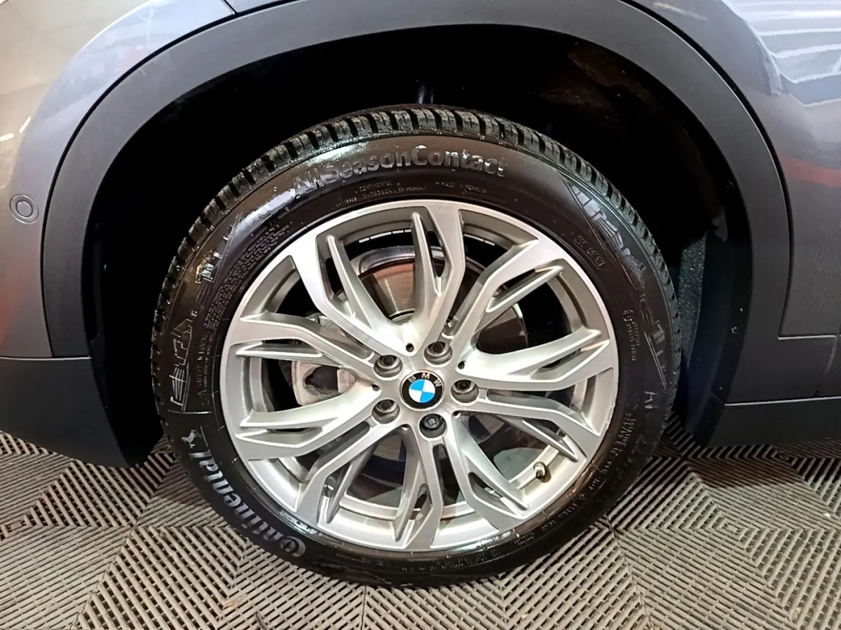 Gros plan sur la roue avant droite avec jante argentée du BMW X2 gris foncé sDrive18i Lounge 2021.