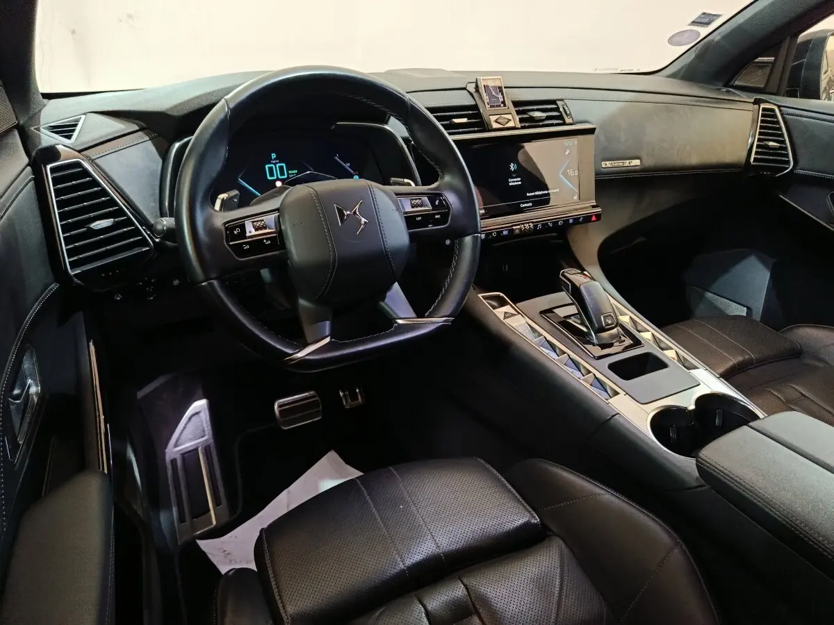 Vue intérieure côté conducteur du DS7 Crossback E-TENSE 4x4 2022, tableau de bord et volant cuir noir avec écran tactile central.