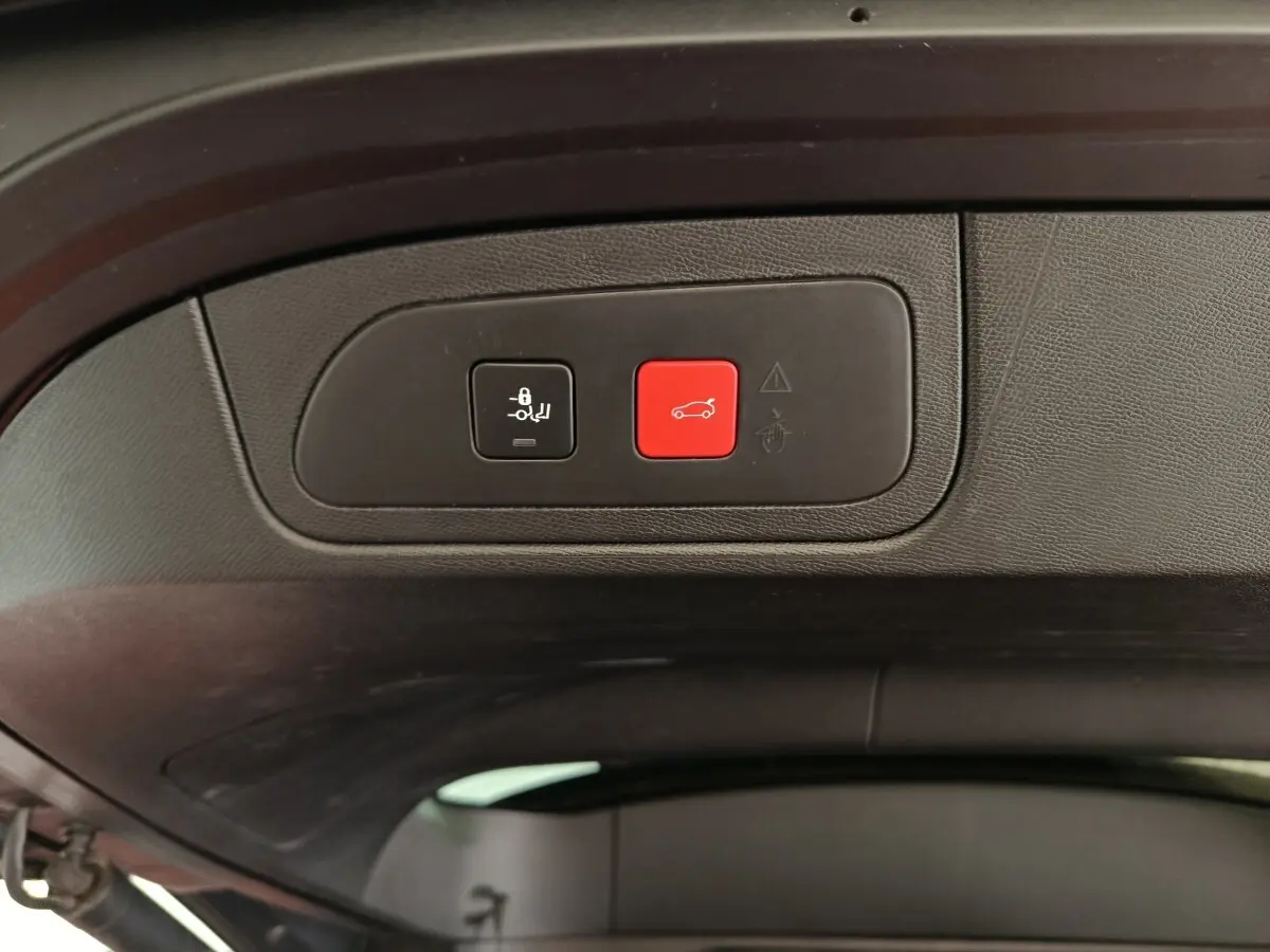 Gros plan sur les boutons de commande du hayon électrique noir et rouge à l'intérieur du coffre du DS7 Crossback noir.