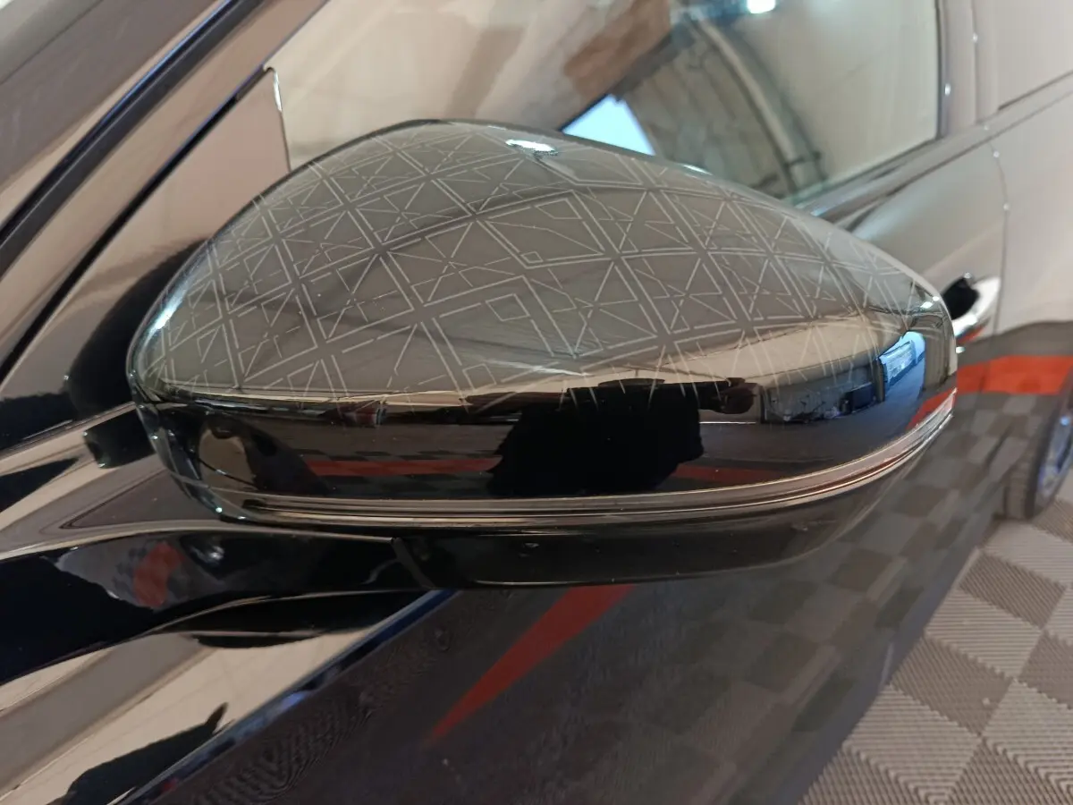 Rétroviseur côté gauche noir brillant du DS7 Crossback E-TENSE 4x4 300 LOUVRE avec motif géométrique gravé.