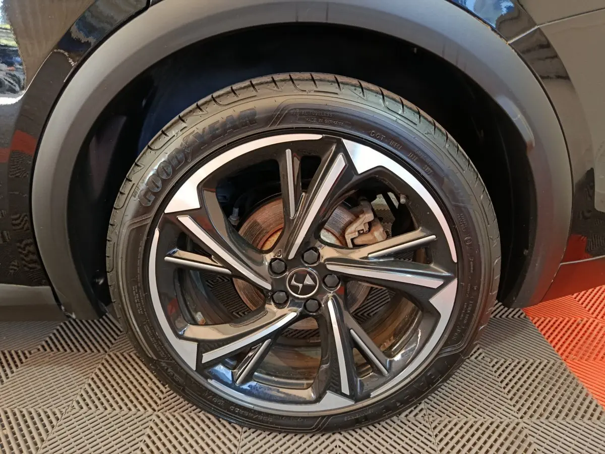 Gros plan sur la roue avant gauche noire du DS7 Crossback E-TENSE 4x4 300 Louvre avec jante alliage stylisée.