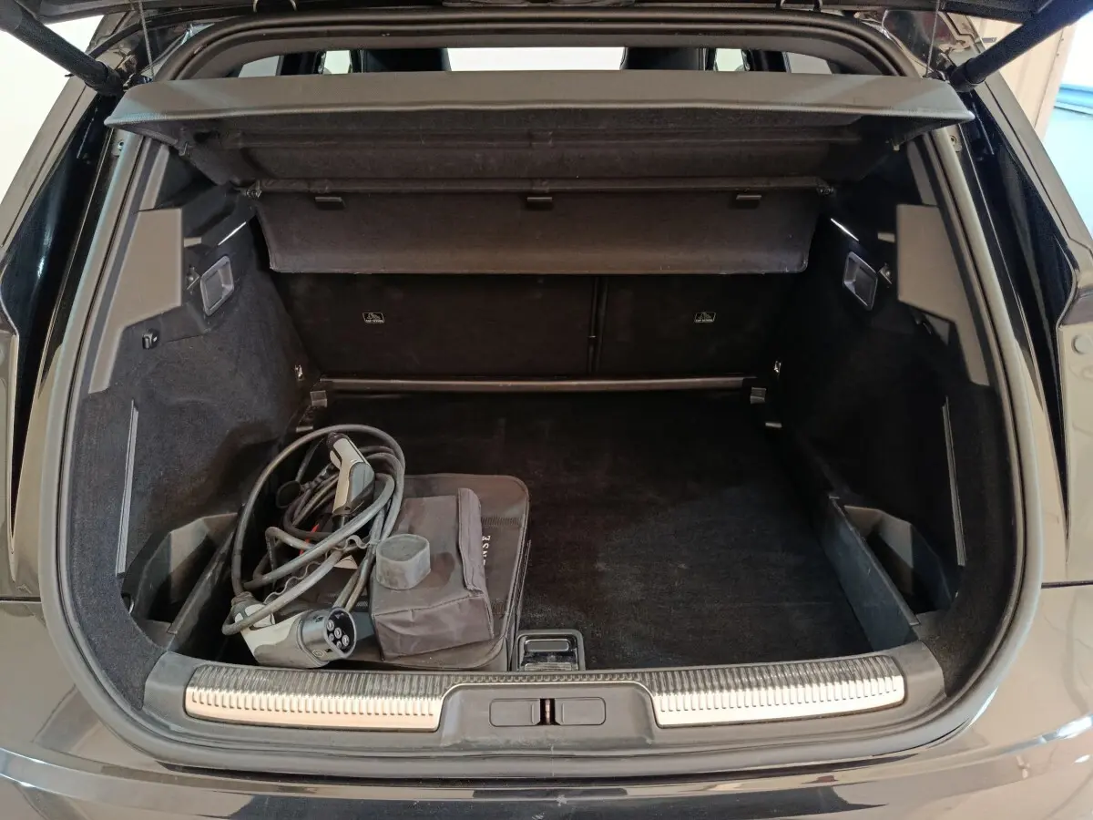 Vue arrière du coffre noir du DS7 Crossback E-TENSE 4x4 300 Louvre avec câble de recharge hybride visible.