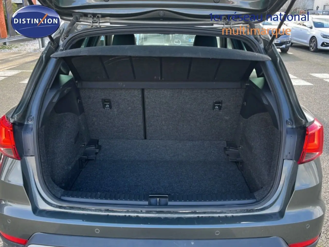 Coffre ouvert vu de l'arrière d'un SEAT Arona gris magnétique métal, montrant un espace de chargement vide et propre.