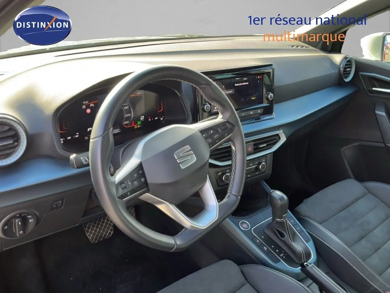 Vue intérieure du poste de conduite du SEAT Arona 2025, volant multifonction et console centrale avec boîte automatique.
