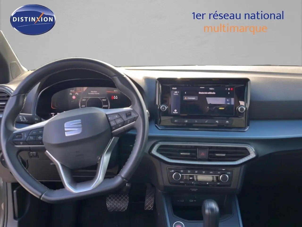 Vue intérieure avant du tableau de bord du SEAT Arona gris magnétique, avec volant multifonction et écran tactile central.