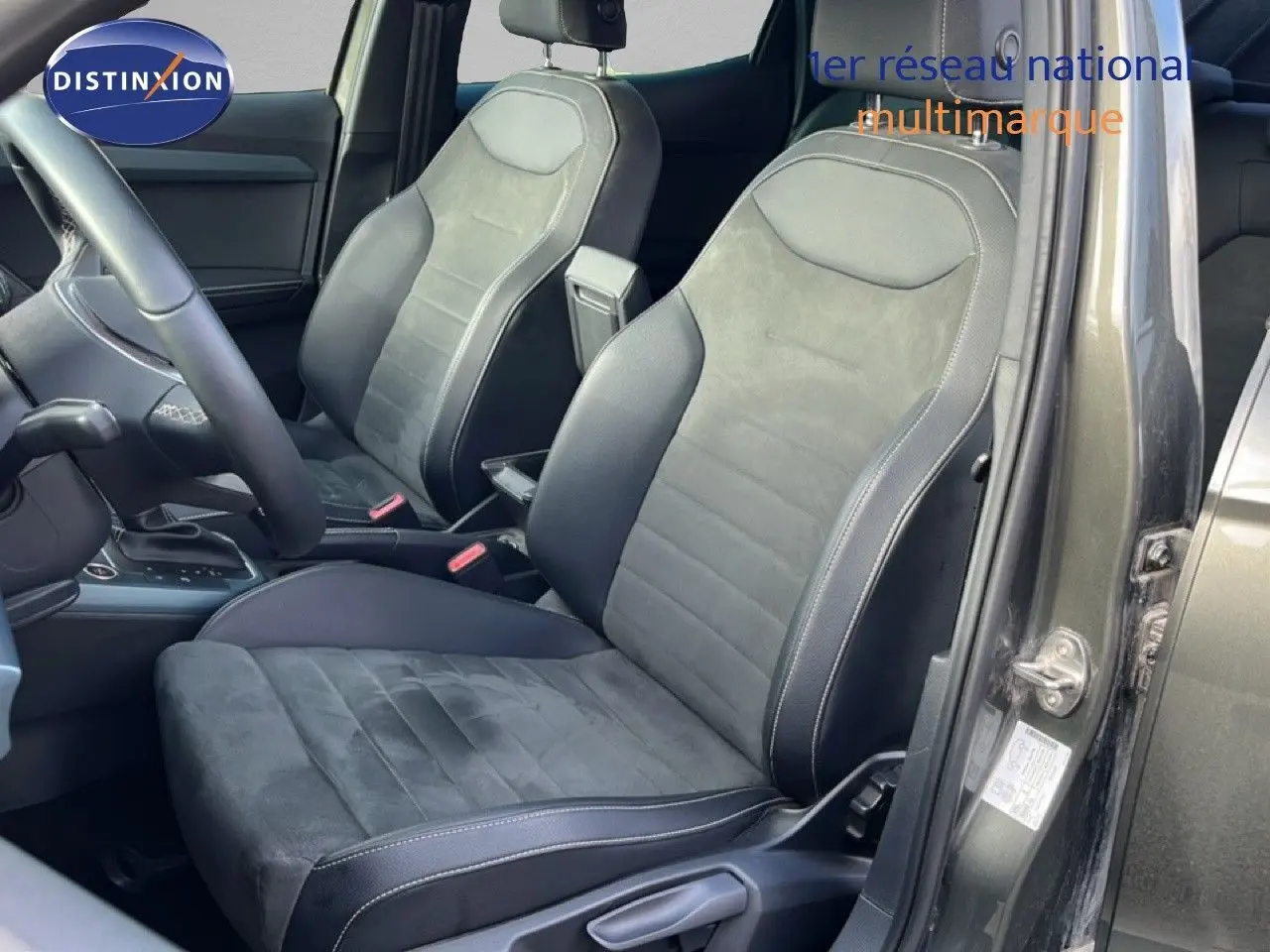 Vue intérieure côté conducteur du SEAT Arona gris magnétique, sièges en cuir et alcantara avec surpiqûres blanches.