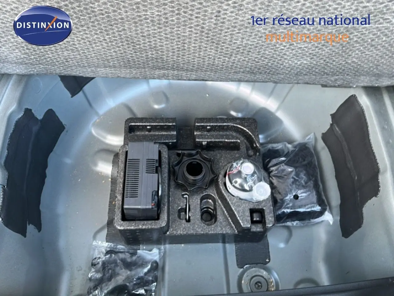 Vue plongeante sur le coffre ouvert d’un SEAT Arona gris métallique, montrant le rangement d’outils et accessoires.