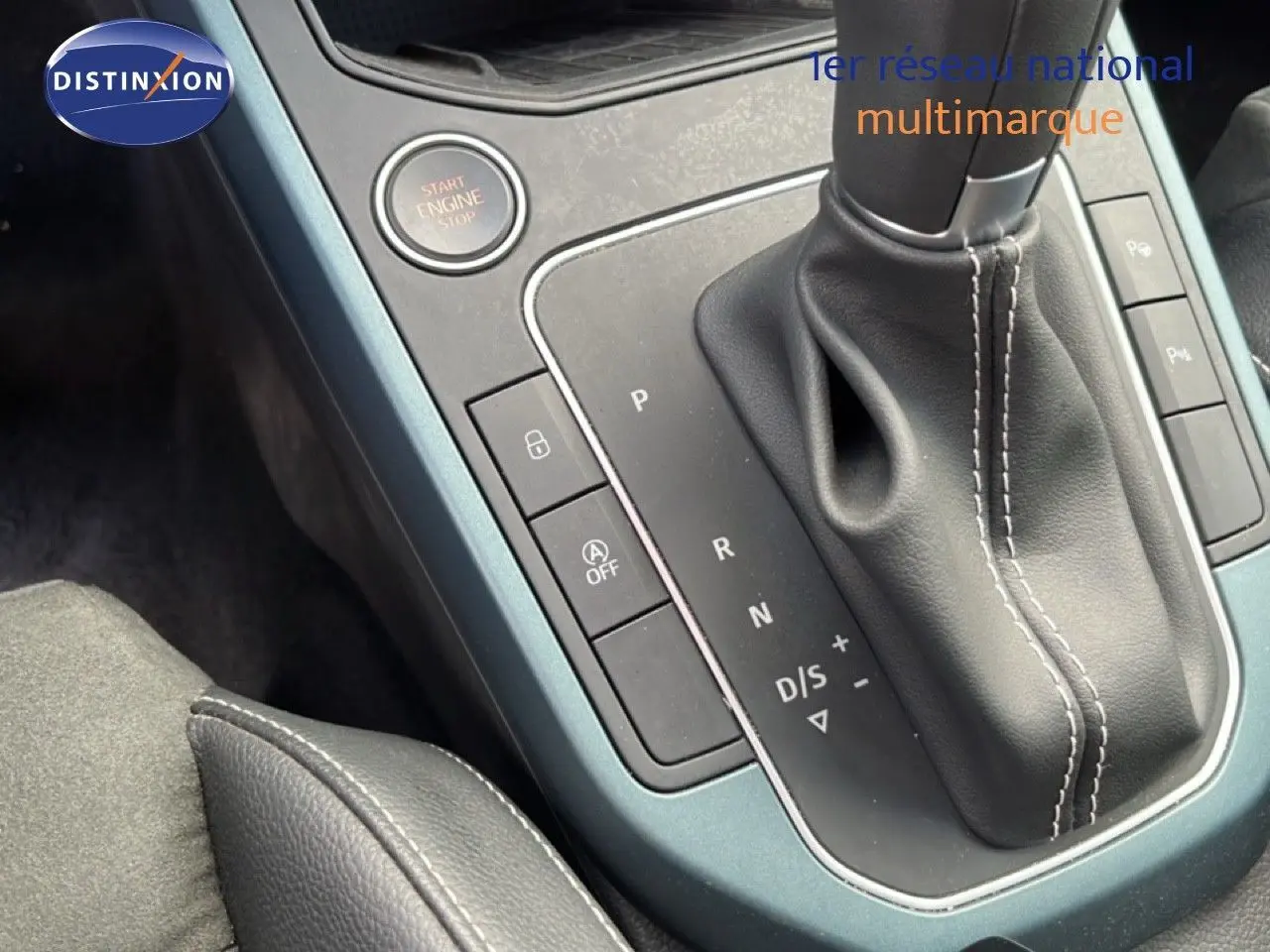 Gros plan sur la console centrale de la SEAT Arona 2025, boîte auto avec levier cuir et bouton start/stop, finition gris métallique.