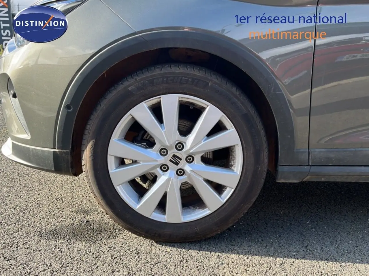 Gros plan sur la roue avant gauche d’un SEAT Arona gris magnétique avec jante alliage et logo central visible.