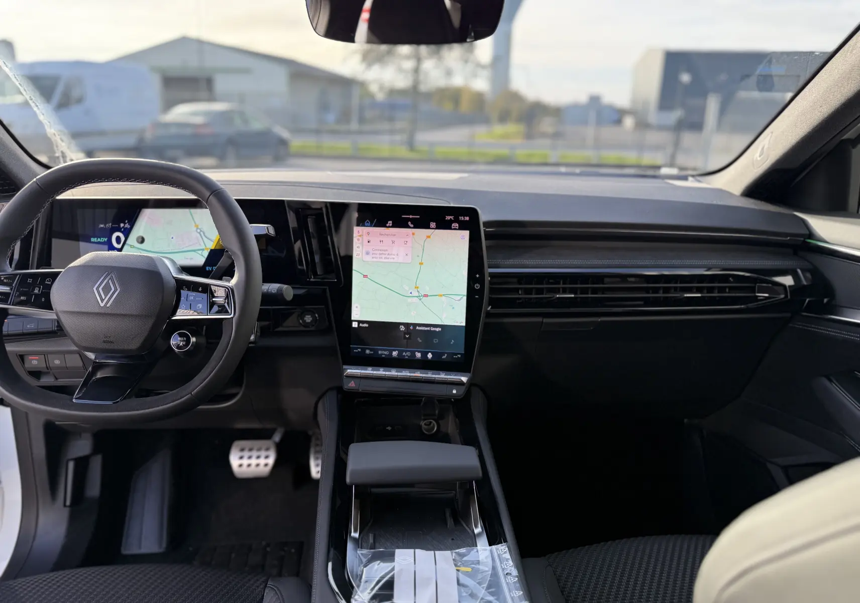 Vue intérieure avant du Renault Austral blanc nacré, mettant en valeur le tableau de bord moderne avec écran tactile central vertical.