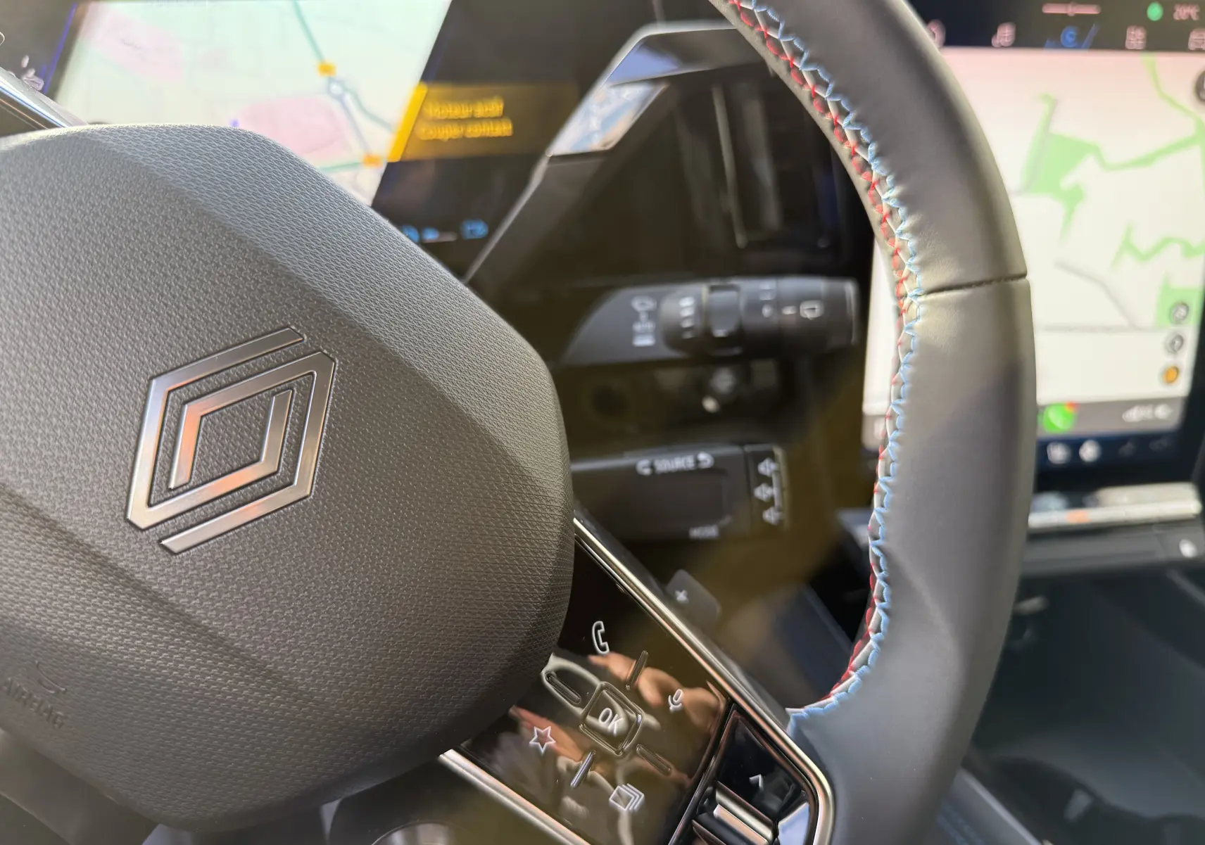 Gros plan sur le volant cuir du Renault Austral 2025 avec commandes intégrées et écran de navigation en arrière-plan.