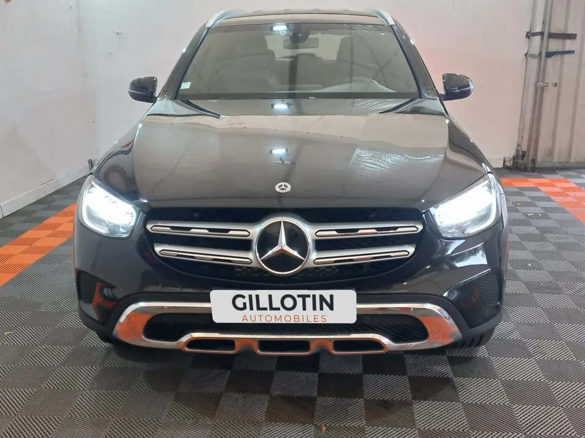 Vue frontale d'un Mercedes GLC 300 E Business Line hybride noir avec phares LED allumés en intérieur.