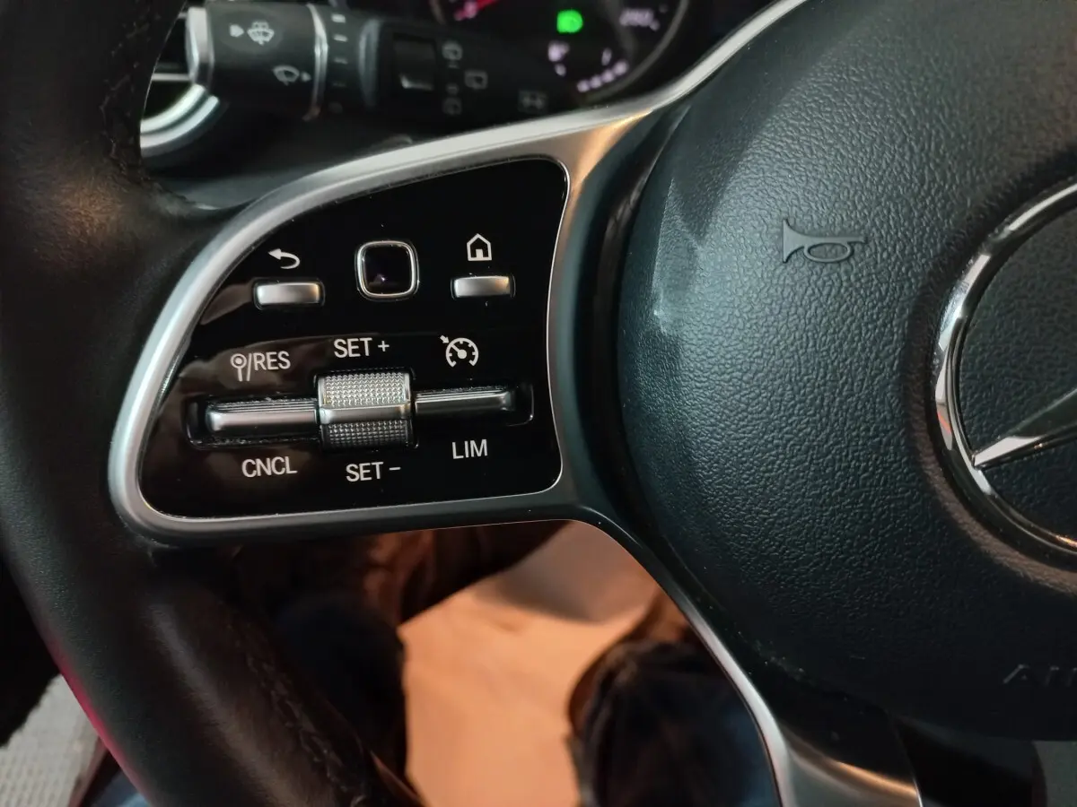 Gros plan sur les commandes du volant côté gauche du Mercedes GLC 300 E Business Line 2021, cuir noir.