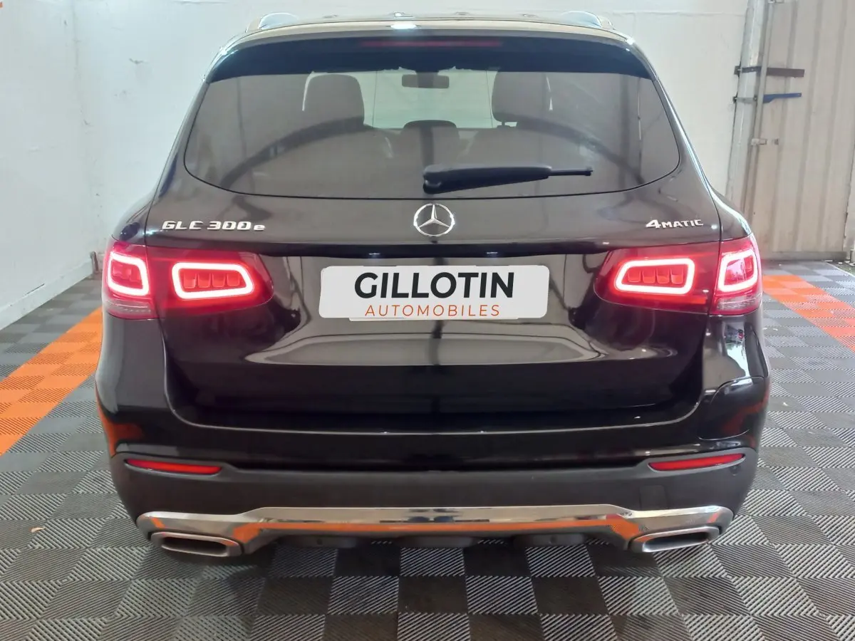 Vue arrière d'un Mercedes GLC 300e noir avec feux LED allumés et logo 4MATIC visible en intérieur.