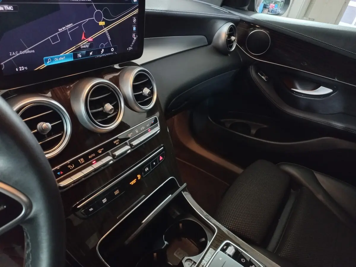 Vue intérieure côté passager du tableau de bord et console centrale en bois noir du Mercedes GLC 300 E Business Line 2021.