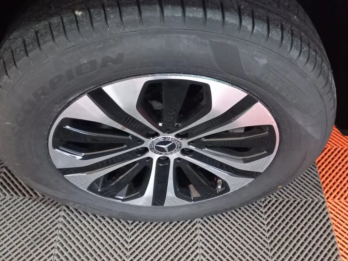 Gros plan sur la roue avant d'un Mercedes GLC 300 E noir avec jante alliage bicolore et logo étoile central