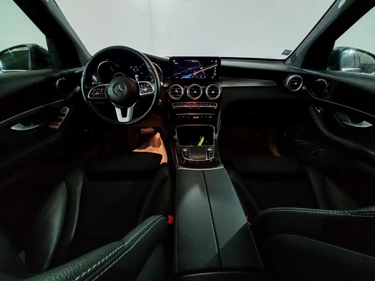 Vue intérieure avant du Mercedes GLC 300 E Business Line 2021, tableau de bord noir avec écran tactile et volant cuir.
