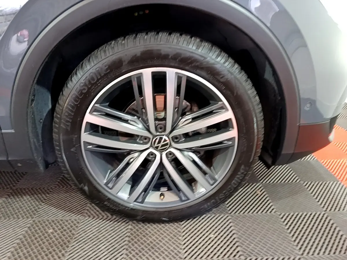 Gros plan sur la roue avant droite gris clair du Volkswagen Tiguan 2.0 TDI 150 DSG7 Elegance 2022 avec jante alliage.