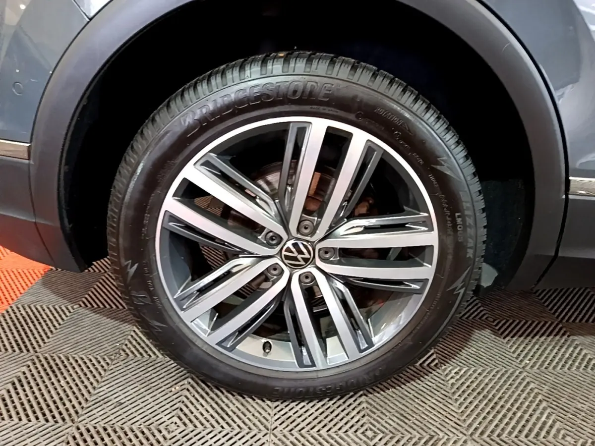 Gros plan sur la roue avant droite du Volkswagen Tiguan gris clair, jante alliage à multiples branches et pneu Bridgestone.