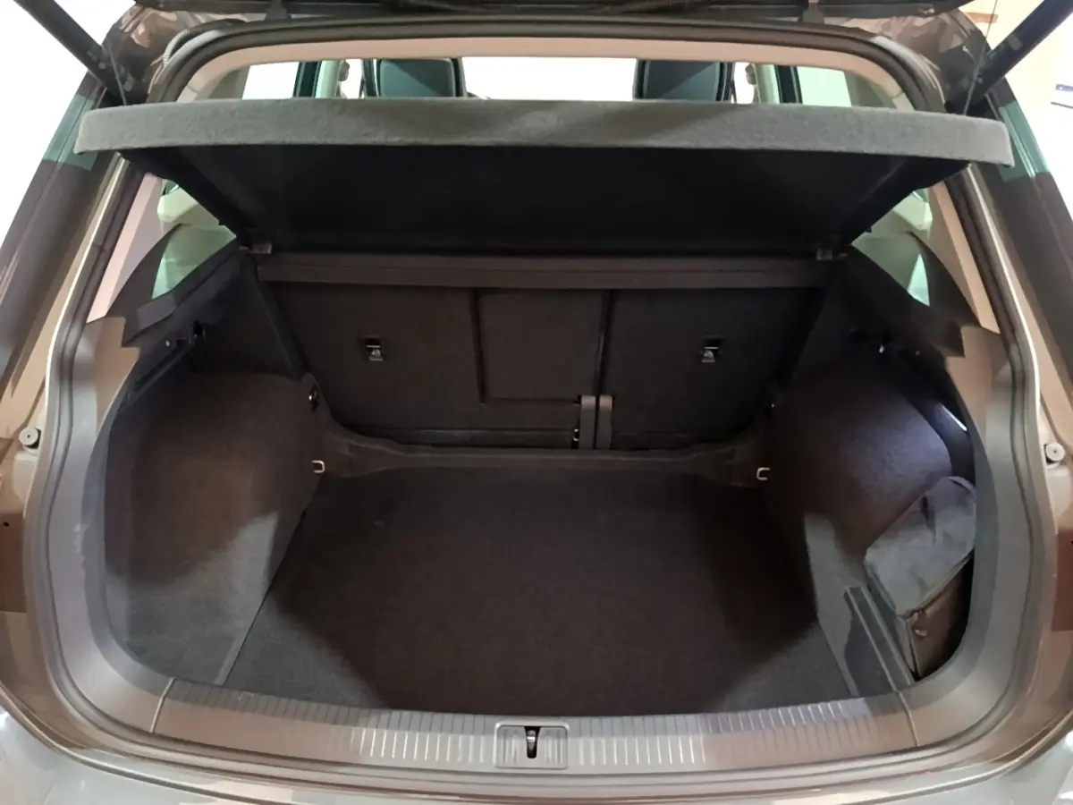 Coffre ouvert du Volkswagen Tiguan gris clair 2022, vue arrière montrant l’espace de chargement vide et la tablette de couverture.