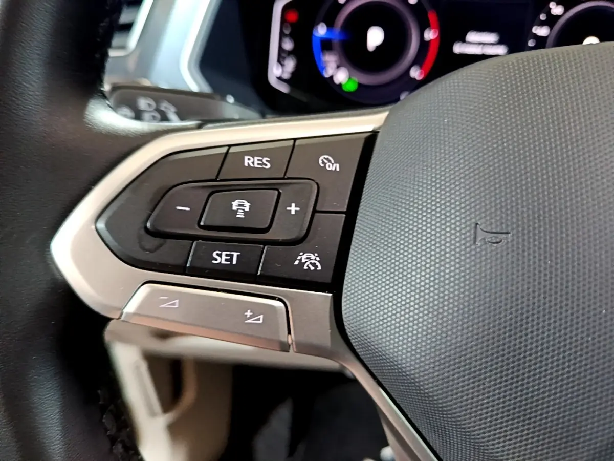 Gros plan sur les commandes de régulateur de vitesse au volant cuir du Volkswagen Tiguan gris clair 2022.