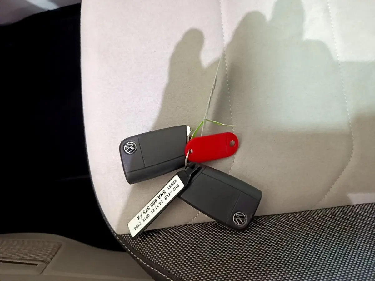 Clés Volkswagen noires posées sur siège clair avec tissu gris foncé, intérieur du Volkswagen Tiguan 2022.