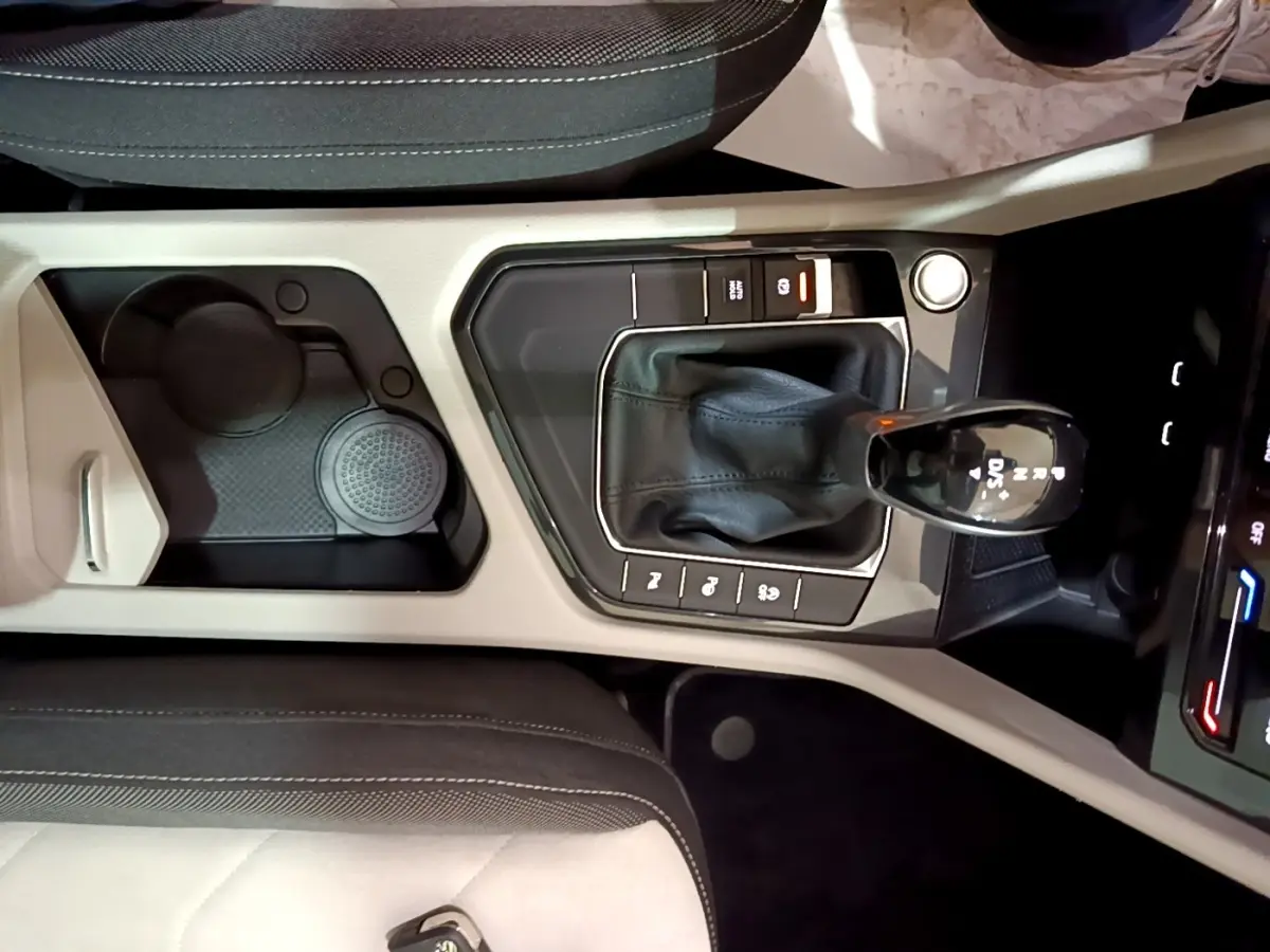Vue plongeante sur la console centrale beige et noire du Volkswagen Tiguan 2022 avec levier de vitesse automatique et rangements.