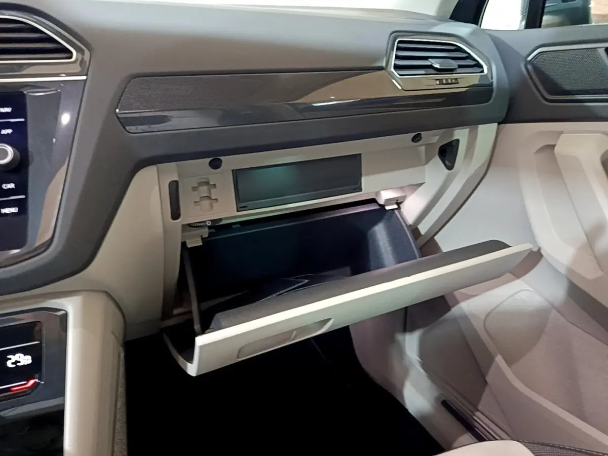 Vue intérieure côté passager du tableau de bord gris clair du Volkswagen Tiguan 2022 avec boîte à gants ouverte.