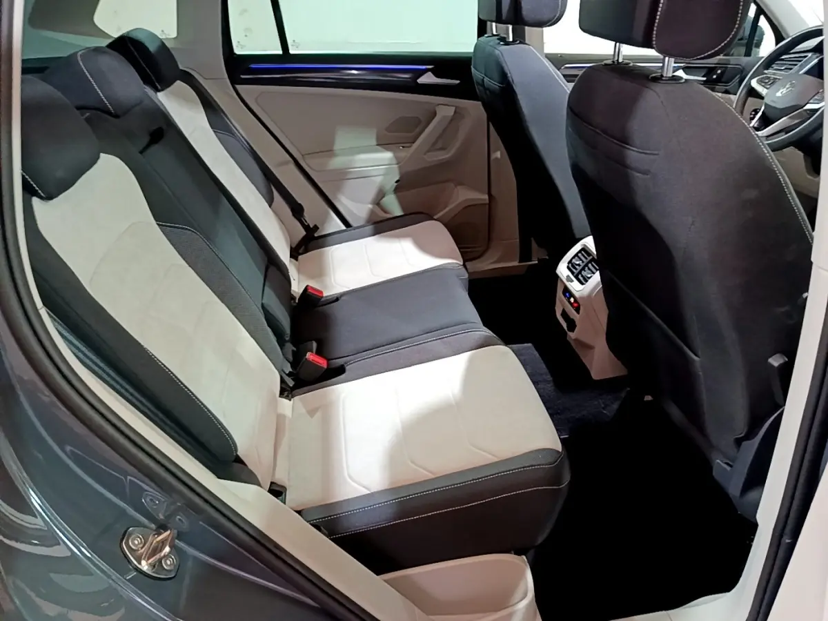 Vue intérieure côté gauche des sièges arrière bicolores noir et beige du Volkswagen Tiguan 2022, avec console centrale visible.