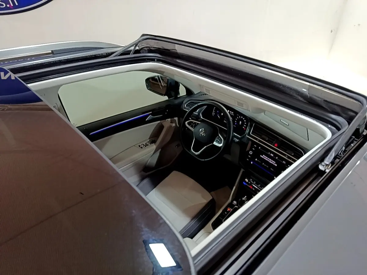 Vue plongeante sur l'intérieur clair du Volkswagen Tiguan gris clair 2022, avec toit ouvrant panoramique ouvert.