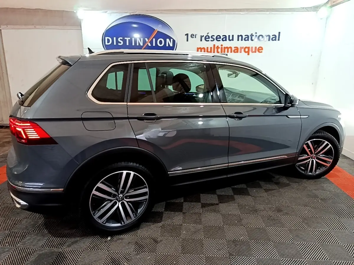 Vue de profil côté droit d’un Volkswagen Tiguan gris clair 2022 avec jantes alliage et feux arrière LED allumés.