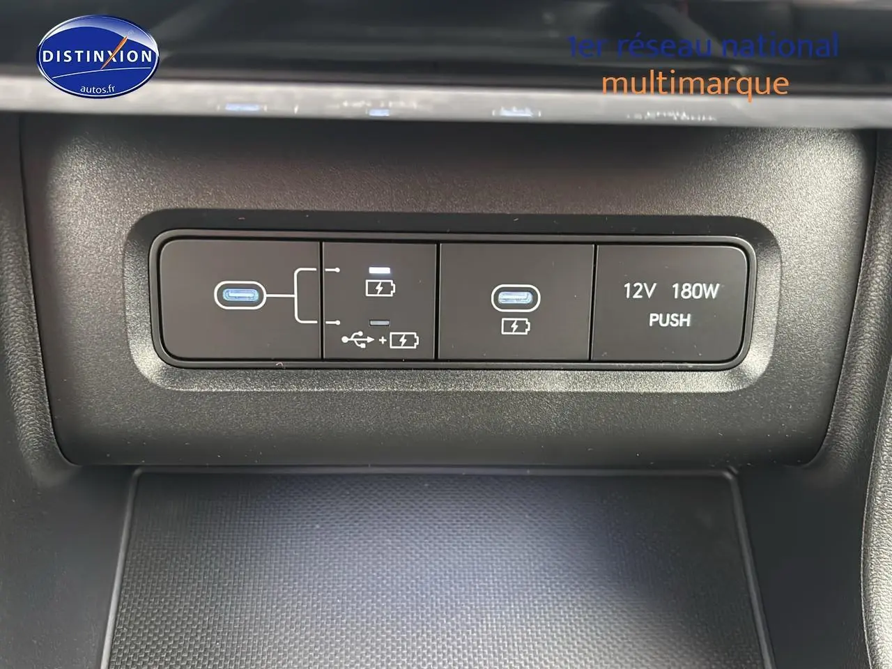 Gros plan sur la console centrale du Hyundai Tucson blanc sérénité, montrant les ports USB et prise 12V.